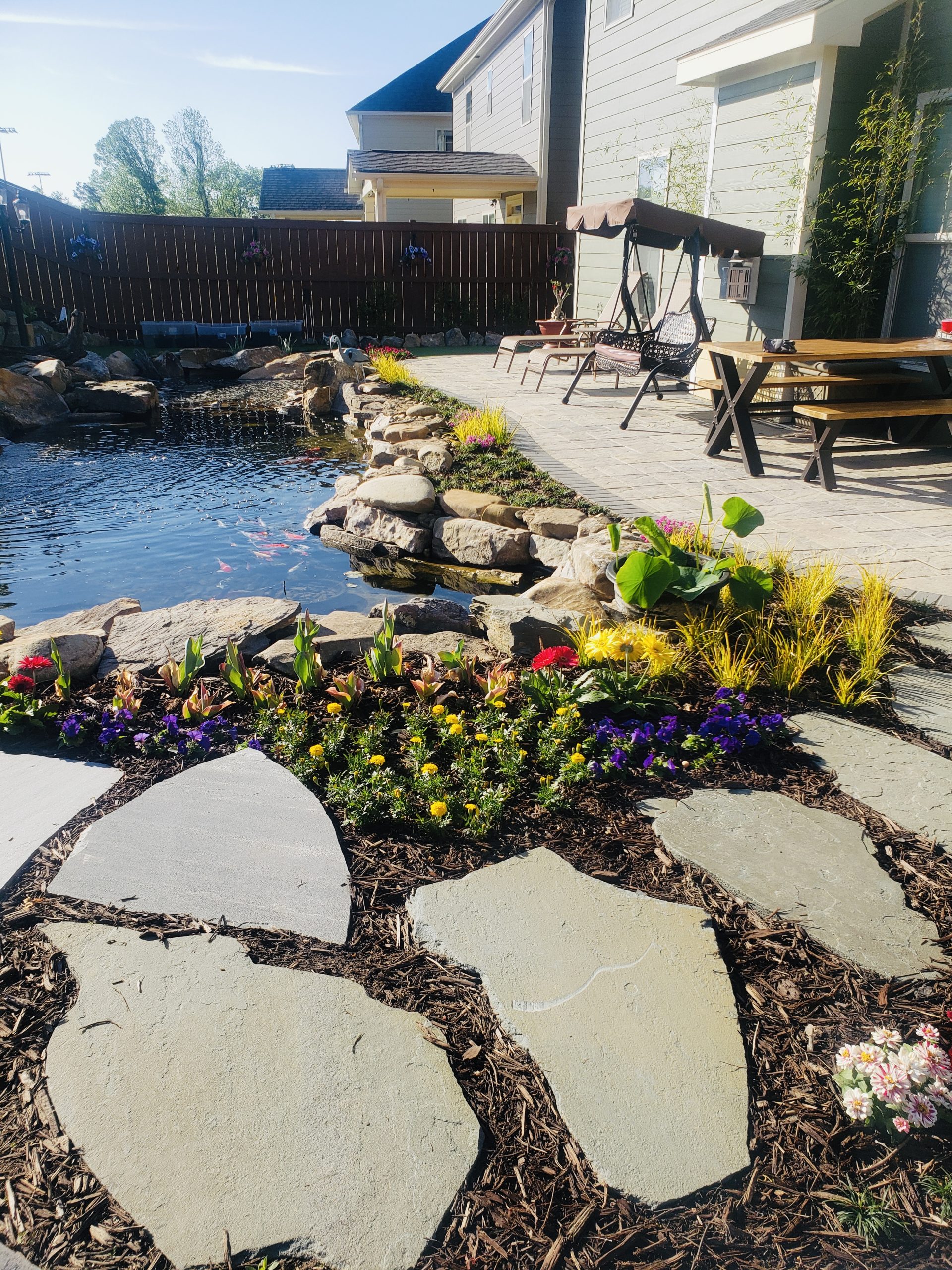 water features, pond, water feature with waterfall, water feature with stone, stone steps, koi pond, water feature with koi fish, stone pathway, stone walkway, flower garden, flower bed, garden installation, hardscaping, stone patio, stone walkway, flagstone, pavers