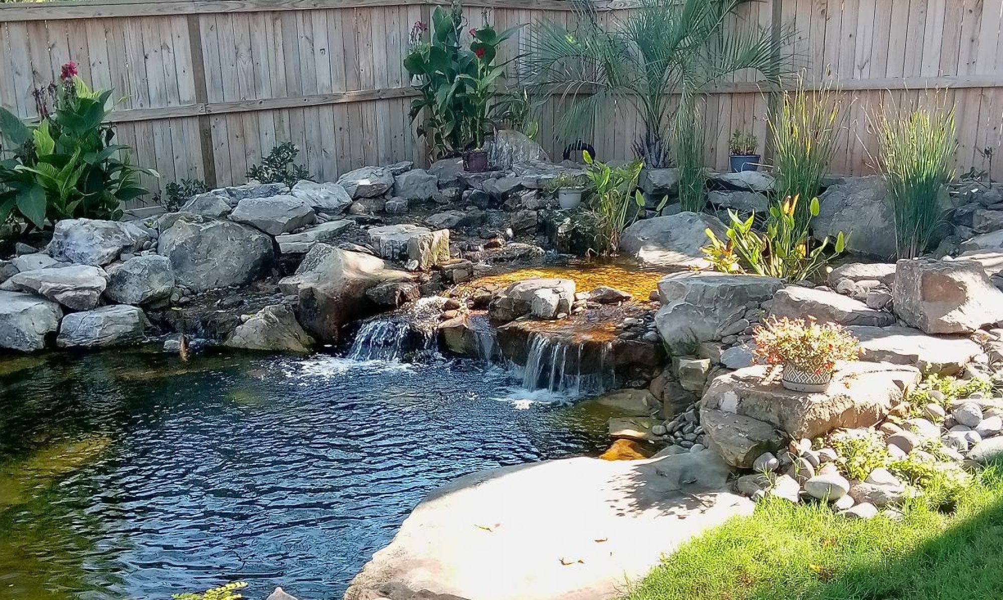 backyard water feature with a waterfall and rocks and stones surrounding a small pond